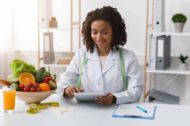 Pretty dietologist black woman working with digital tablet at workplace functional nutritionist